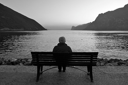 Elderly man sitting alone near lake