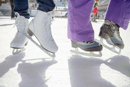 close up of two people wearing skates on ice