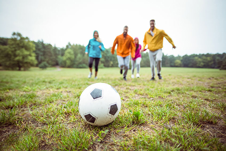 Friends running towards football in the countryside