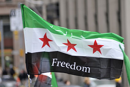 A protester waiving a Syrian flag during a protest rally organized to raise awareness and commemorat