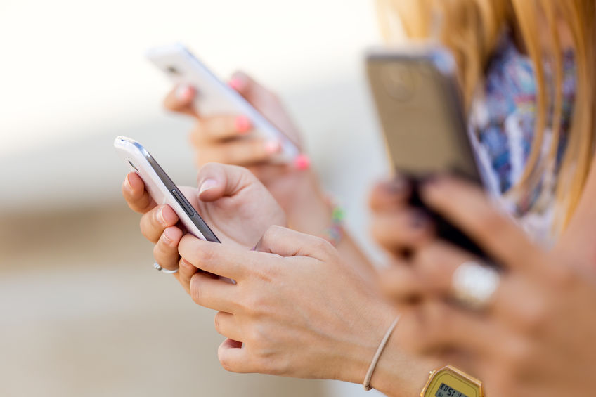 Portrait of three girls chatting with their smartphones at the campus