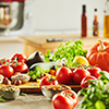 Side view of assorted vegetables including tomatoes and pumpkins covering cutting board in front of 