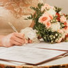 Bride's hand puts signature pen on consent to marry at wedding close-up.