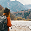 woman with a backpack near the river on nature in the mountains