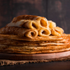 Traditional Russian food - thin pancakes. A stack of crepes on a dark brown wooden background. Rusti