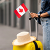 Cropped of woman traveller holding flag of Canada, going abroad