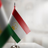 Small flags of the Tajikistan on an abstract blurry background.