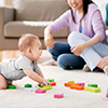 happy mother, father and baby boy playing toy blocks at home