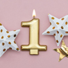 Number 1 gold candle and stars on a pastel pink background