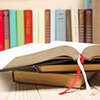 Open book, hardback books on wooden table.