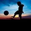 silhouette of boy kicking ball