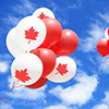 Canadian maple leaf flag and balloons in the sky for canada day.