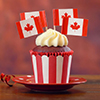 Red and white theme cupcakes with Canadian maple leaf flags for first of July Canada Day or Canadian