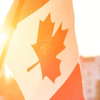 Mini flag of Canada in front of sun