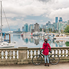 Stanley Park - woman with cycle standing on a bridge over water