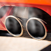 Close up of red car tailpipe showing exhaust smoke
