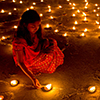 2 women lighting candles in clay lamps