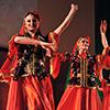 3 women in red traditional attire dancing, celebrating Nowruz