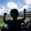 Child standing and cheering at a baseball game. Silhouette view from behind