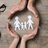 Close up of female and male hands protecting a paper chain family.