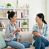 Two friends talking with coffee mugs on couch