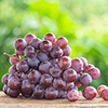 Bunch of ripe red grapes on wooden table with green space blur background
