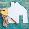 House icon and keys on wooden background