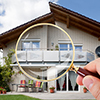 Person Hand With Magnifying Glass Over Luxury House