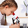 Young kids in science lab study samples under the microscope - biology class