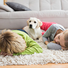 Cute silblings with their puppy on rug at home in the living room