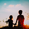 little boy and girl silhouettes holding hands at sunset