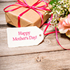 Bunch of flowers and tag with text on wooden background. Happy Mothers Day