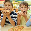 Three little boys eating pizza at cafe