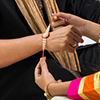  young sister tying traditional Rakhi Thread on brother's wrist
