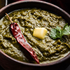Sarson Ka Saag served with roti in dark coloured dishes