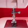 Close up photo of white sewing machine - red background