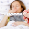 thermometer with fever reading over blurred image of sick person