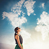 woman with suitcase ooking at clouds - shaped like world map