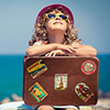 girl holding suitcase on beach with stickers