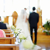 Blurred image of couple getting married in church. Seated woman in focus.