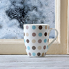 Cup of hot drink by cold and wet window