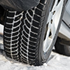 Car with winter tyres installed on light alloy wheels in snowy outdoors road