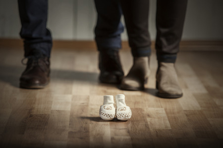 focus of baby boots with parents feet visible behind