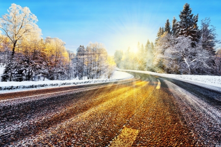 Winter road with sunlight reflecting on asphalt