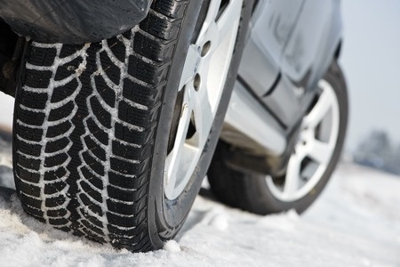 Car with winter tyres installed on light alloy wheels in snowy outdoors road
