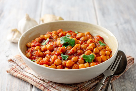 Spicy Chickpea curry Chana Masala in bowl on wooden table. Traditional Indian dish. Selective focus.
