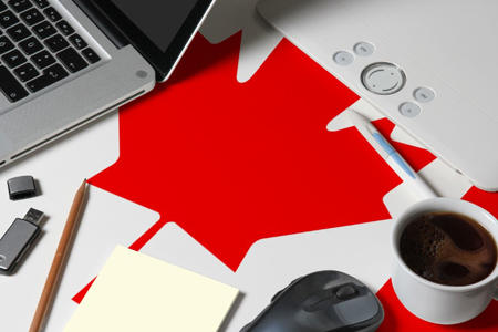 Canada national flag on top view work space of creative designer with laptop, computer keyboard, usb