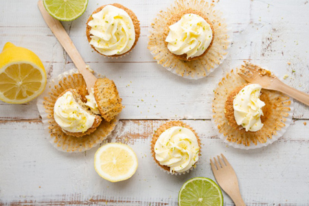 Lemon and poppy seed cupcakes with cheese cream frosting and lemon and lime zest on a rustic white w