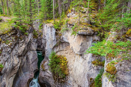 The Canadian Rockies. Cool cloudy day. Powerful waterfall in a picturesque gorge Maligne Canyon. Coo