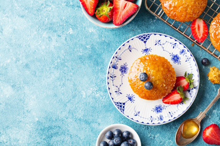 Muffin, cupcake with fresh berries on a plate. Blue background. Top view. Copy space.